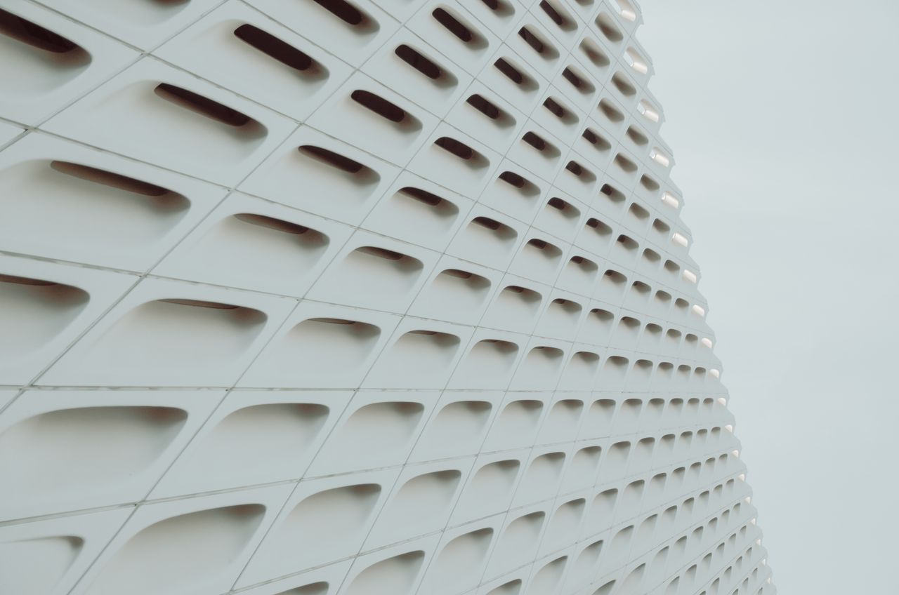 Services Abstract view of a white geometric building facade with grid pattern design.