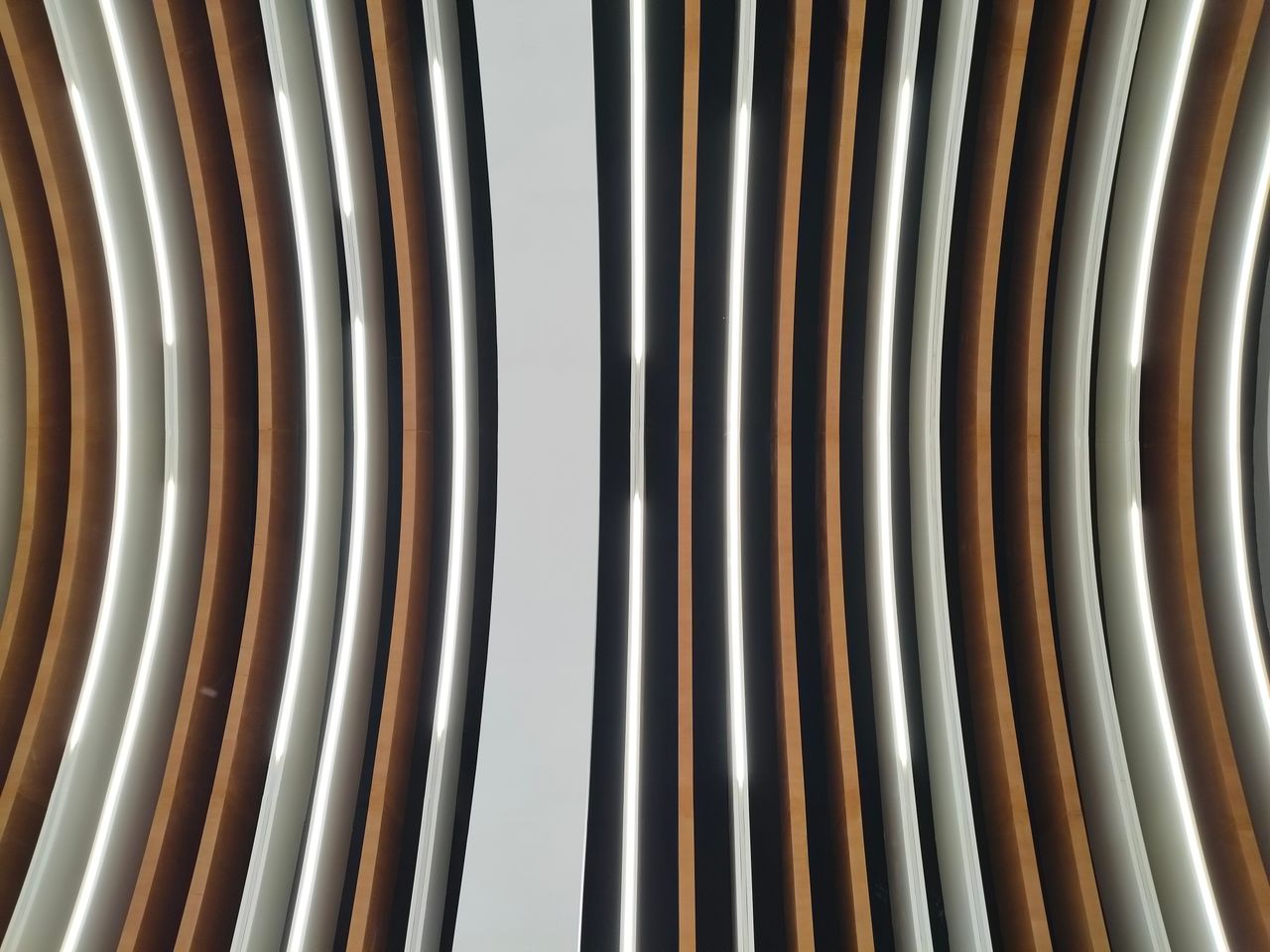 Services A captivating view of a modern ceiling design featuring curved lines and alternating colors.